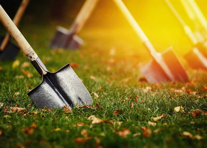 naem-2018-article-closeup-shovel-stuck-green-lawn-yellow-700x500
